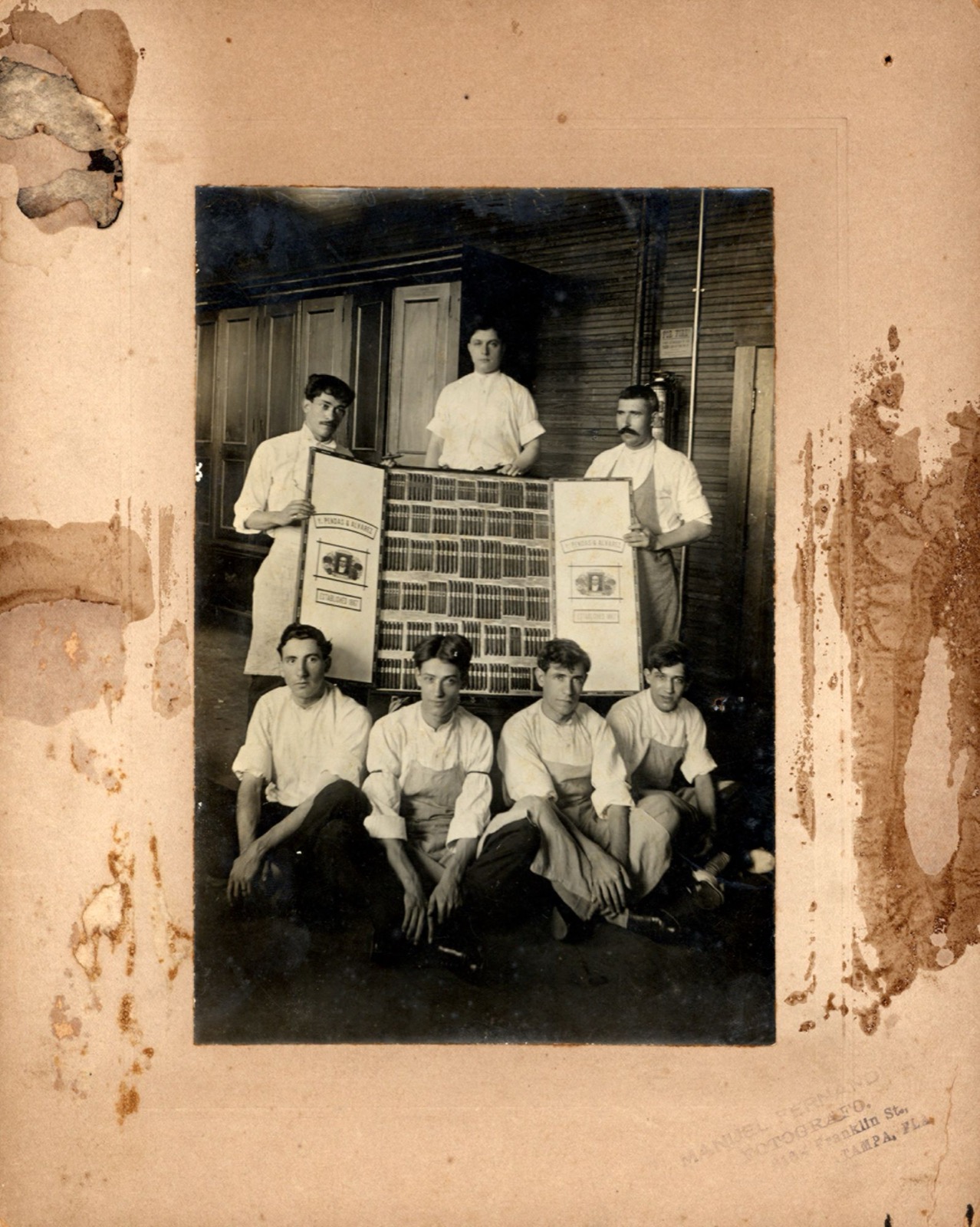 Seven Pendas and Alvarez cigar workers posing with a display of cigars